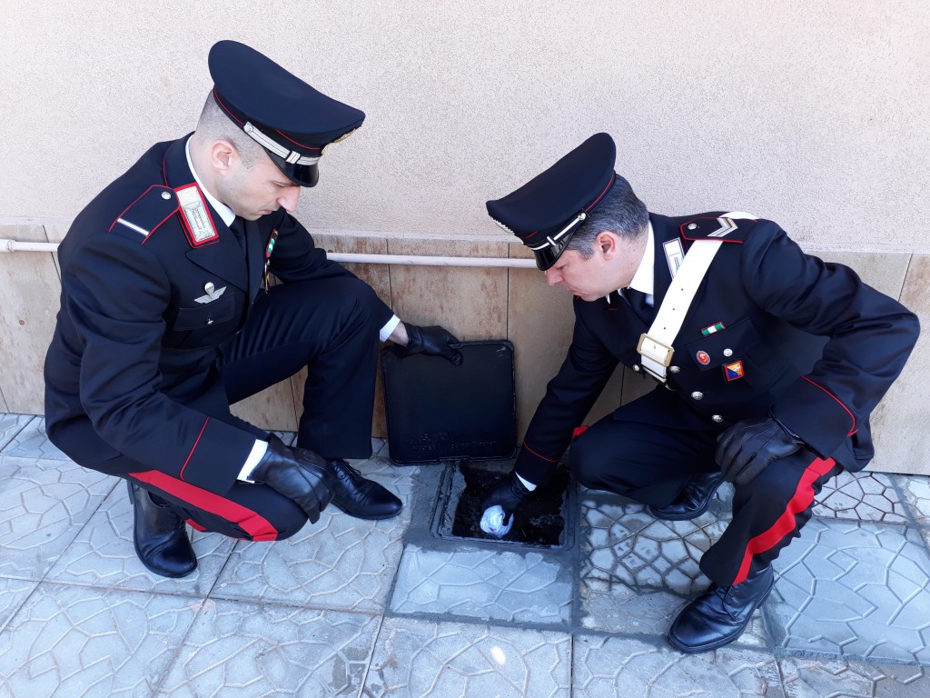 Foto di due militari dell'Arma che recuperano della cocaina gettata in uno scarico