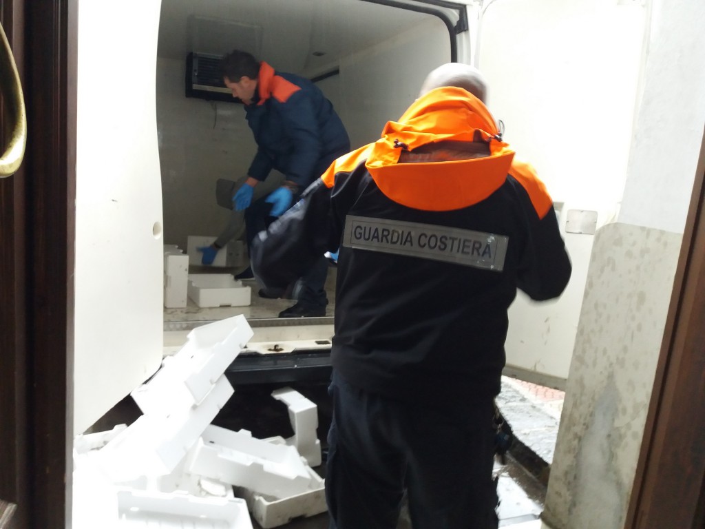 Foto che ritrae gli agenti della guardia costiera mentre sequestrano le casse di novellame