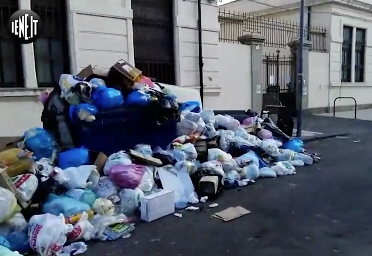 foto dei cassonetti colmi di immondizia e dei sacchetti gettati in strada di fronte alla scuola elementare cesare battisti di Messina in un servizio de Le ieie