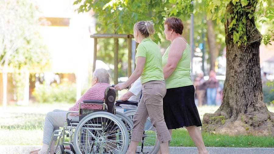 foto di un'anziana sulla sedia a rotelle con la badante