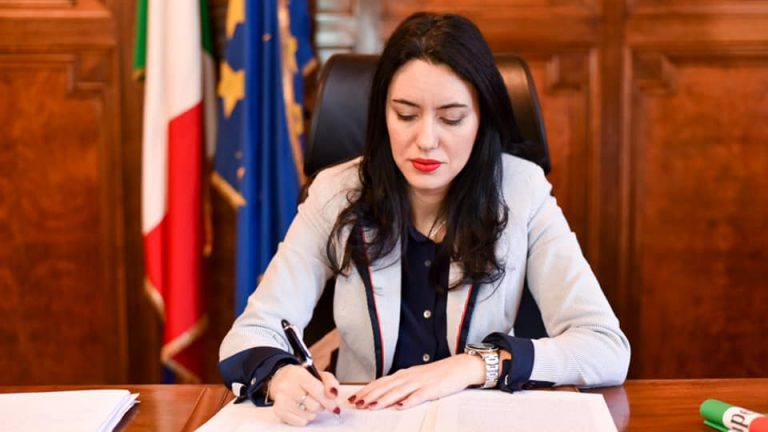 foto del ministro dell'istruzione Lucia Azzolina alla scrivania che firma delle carte