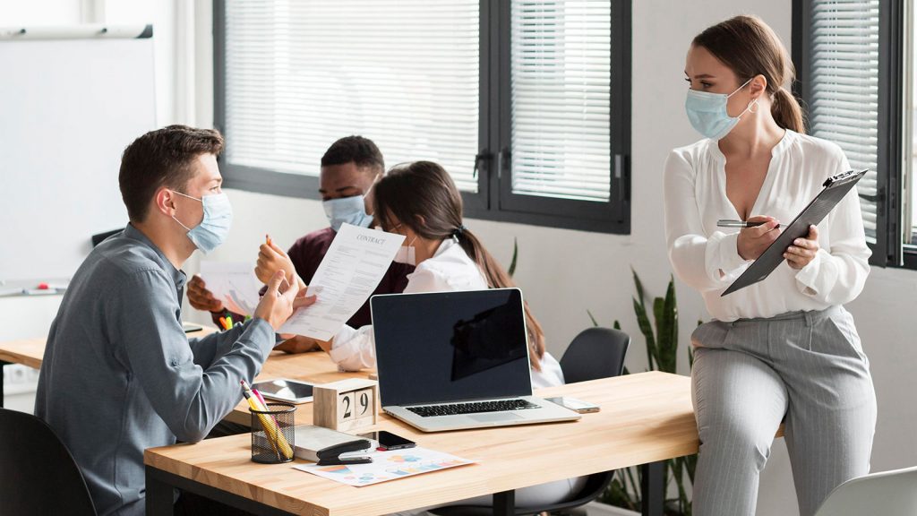 foto di colleghi in ufficio con le mascherine per il coronavirus durante il lavoro