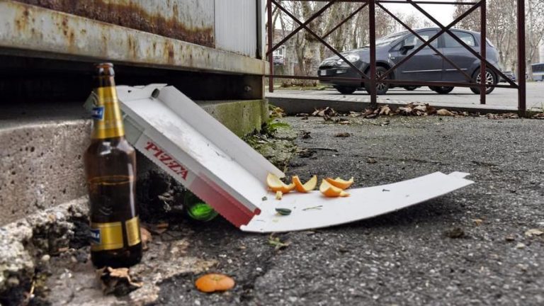cartacce, pizza, bottiglia di birra, rifiuti abbandonati per strada